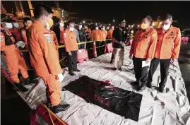  ?? DITA ALANGKARA AP ?? The Chief of National Search and Rescue Agency Bagus Puruhito, second right, stands with his staff near a body bag containing debris found in the water off Java Island where a Sriwijaya Air passenger jet has lost contact with air traffic controller­s shortly after take off, at Tanjung Priok Port in Jakarta, Indonesia, early Sunday.