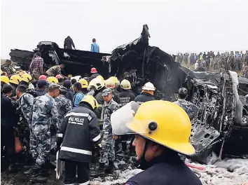  ?? AP ?? Nepalese rescuers stand near a passenger plane from Bangladesh that crashed at the airport in Kathmandu, Nepal, yesterday.