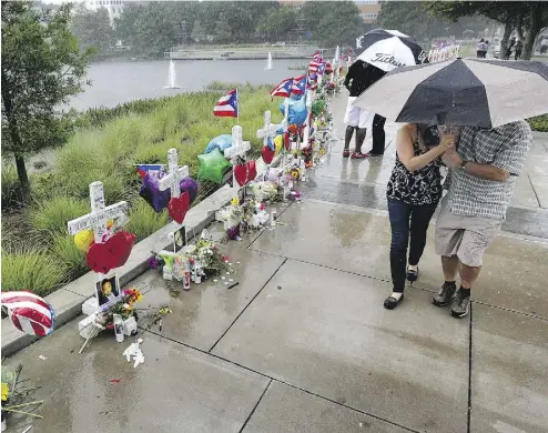  ?? JOE BURBANK / ORLANDO SENTINEL ?? Visitors brave the rain to view the 49 crosses at the makeshift memorial outside Orlando Regional Medical Center on Sunday. The crosses were erected by an Illinois man to honour each of the victims in the Pulse massacre.