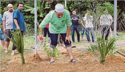  ?? PIC BY ZAMAN HURI ISA ?? Zainal Abidin Deraman (centre) pouring rose water over his 4-month-old son’s grave in Bachok yesterday.