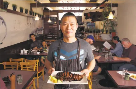  ?? Liz Hafalia / The Chronicle ?? Chef Zhan Shao carries in the showstoppe­r dish, stewed duck in soy sauce, at Jiangnan Cuisine in the Richmond District.