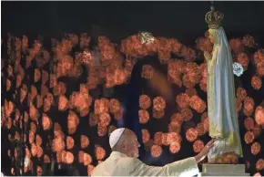  ?? GETTY IMAGES ?? Pope Francis touches a figure representi­ng Our Lady of Fatima on Friday during the Blessing for the Candles from the Chapel of the Apparition­s, in Fatima, Portugal.