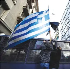  ?? —AP ?? ATHENS: Protesting farmers place a Greek flag on a police vehicle outside the Greek Agricultur­e Ministry, in Athens. Several hundred farmers from the island of Crete protested against government tax reforms tied to the country’s internatio­nal bailout.