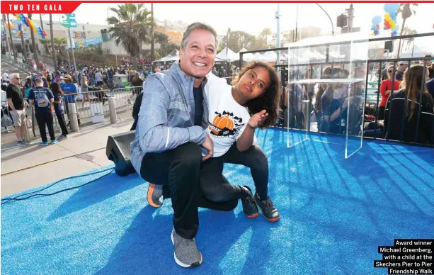  ?? Award winner Michael Greenberg, with a child at the Skechers Pier to Pier Friendship Walk ??