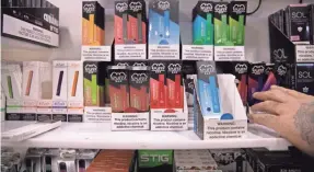  ?? MARSHALL RITZEL/AP ?? Various brands and flavors of disposable vape devices on display at a store in the Brooklyn borough of New York last month.