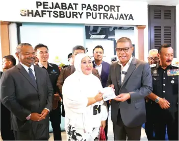  ?? — Bernama photo ?? Saifuddin (second right) presenting a passport to Zunaida Othman (second left) at the opening of the Shaftsbury Passport Office in Putrajaya on Monday.