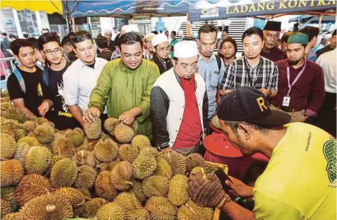  ??  ?? JEMAAH yang baru selesai menunaikan solat Jumaat mengambil kesempatan membeli durian sempena Program Jom Makan Buah.