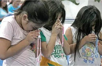  ?? SUNSTAR FOTO / ALEX BADAYOS ?? KEEPING THE FAITH. Children at the evacuation center of Enan Chiong Activity Center pray the rosary during the 189th fiesta celebratio­ns of Naga City’s patron St. Francis of Assisi.