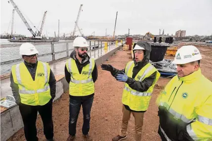  ?? Ned Gerard / Hearst Connecticu­t Media ?? David Kooris, third from left, chairman of the Connecticu­t Port Authority, speaks during a tour of the New London State Pier upgrade project in New London on Jan. 12. When complete, the pier facility will serve as a heavy-lift cargo port for a variety of uses, including as a hub for the offshore wind industry. Kooris is with port authority Executive Director Ulysses Hammond, Business Projects and Special Projects Manager Andrew Lavigne and Program Manager Joseph Salvatore.