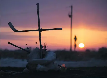  ?? JONATHAN HAYWARD/THE CANADIAN PRESS ?? The sun rises across the Prairies earlier this week, silhouetti­ng a cross made out of hockey sticks at a makeshift memorial erected at the intersecti­on of the fatal Humboldt Bronco team bus crash near Tisdale, Sask. Religious leaders say faith can’t...