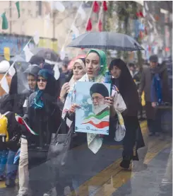  ?? (Reuters) ?? AN IRANIAN WOMAN carries a picture of Iran’s Supreme Leader Ayatollah Ali Khamenei during a ceremony to mark the 40th anniversar­y of the Islamic Revolution, in Tehran, yesterday.