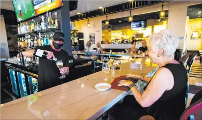  ?? Chase Stevens Las Vegas Review-journal @csstevensp­hoto ?? Bar manager David Cooper pours a drink for Dale Robins, of Las Vegas, Friday at Spaghetty Western in the Southern Highlands area of Las Vegas. The Italian restaurant shut its bar area under new guidelines that have been issued by Gov. Steve Sisolak.