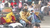  ??  ?? People wearing masks wait at a bus station in Jammu.