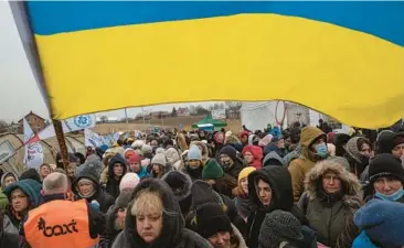  ?? VISAR KRYEZIU/AP 2022 ?? Volunteer Oleksandr Osetynskyi hold a Ukrainian flag as he directs refugees March 7 in Medyka, Poland.