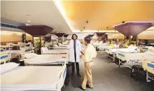  ?? AP ?? A doctor briefs a health worker before the opening of a Covid-19 care centre at a banquet hall in New Delhi.