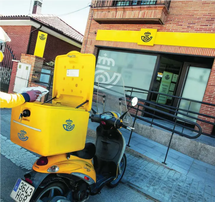  ?? CORREOS ?? Un empleado de Correos introduce un paquete en su moto antes del reparto