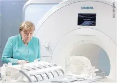  ??  ?? German Chancellor Angela Merkel inspects a magnetic resonance imaging machine during a visit to Siemens Healthinee­rs in Shenzhen, China in May this year.