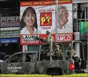  ?? AP ?? A military patrol drives past a political propaganda banner for Laura Caballero, a candidate for the Guerrero state legislatur­e. Three years ago Caballero closed her restaurant after organized crime tried to extort her.