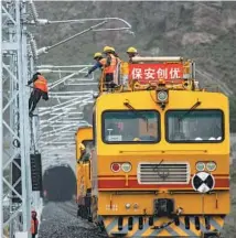  ?? REN FUYANG / XINHUA ?? Workers install an overhead catenary system for the Lhasa-Nyingchi electrifie­d railway in mid-August in Sangri county, Lhokha city, Tibet.