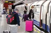  ?? PTI ?? People wearing face masks who landed on flights at Heathrow Airport board an undergroun­d train bound eastbound into London, at the Heathrow Terminals 2 & 3 tube station, in London, Monday