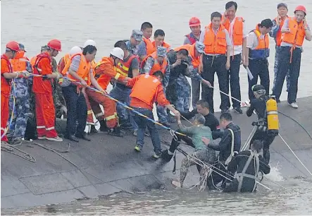  ?? GETTY IMAGES ?? A survivor is rescued by divers from the Eastern Star cruise ship that capsized in the Yangtze River in central China. At least 15 people were brought to safety as divers raced to find survivors on Tuesday. More than 450 people, most of them elderly,...