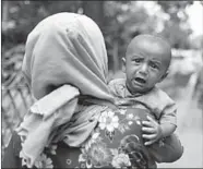  ??  ?? A Muslim woman who has fled across the border into Bangladesh carries her child. (Photo: Reuters.com)