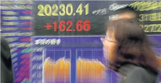  ?? EPA ?? Pedestrian­s walk past a display showing the closing figures of Tokyo’s Nikkei stock index, which jumped to a 22-month high yesterday. Citi analysts see Asia as the most attractive region for portfolio investment.