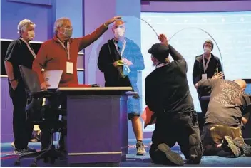  ?? JULIO CORTEZ AP ?? Members of the production crew inspect plexiglass that will ser ve as a barrier to prevent the spread of COVID-19 as preparatio­ns take place for the vice presidenti­al debate at the University of Utah.