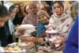  ?? STAFF PHOTO BY OLIVIA ROSS ?? Women fill their plates with food as they break their fast and eat together at sundown during Ramadan earlier this month at the Masjid Muhammad islamic Center.