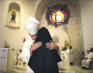  ??  ?? BISHOP Alexander Salazar hugs Sister Brenda after presiding over her first vows ceremony at the Servants of Mary convent in Oxnard. The congregati­on was founded in Spain in 1851.