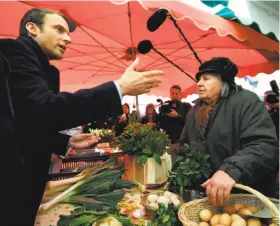  ?? Eric Feferberg / AFP / Getty Images ?? French centrist presidenti­al candidate Emmanuel Macron speaks with a vendor at a market in Poitiers. The final round of voting will take place May 7.