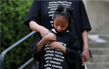  ??  ?? ‘USE OUR VOICE’: Nina Simone Dear, 5, stands with her mother, Simone, before a funeral procession to memorializ­e the lives of George Floyd, Ahmaud Arbery and Breonna Taylor on Sunday.