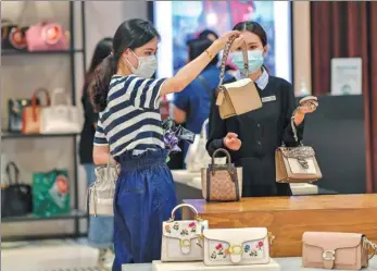  ?? LUO YUNFEI / CHINA NEWS SERVICE ?? Tourists buy handbags at a duty-free shop in Haikou, Hainan province.