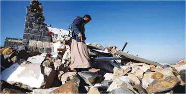  ?? (Mohamed al-Sayaghi/Reuters) ?? A MAN WALKS atop the rubble of a house that was hit by a Saudi-led air strike north of Yemen’s capital Sanaa yesterday.