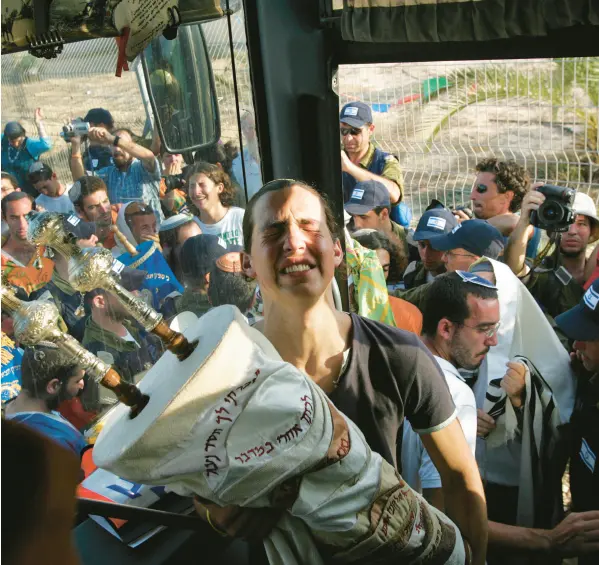  ?? RUTH FREMSON/THE NEW YORK TIMES ?? A settler cries as he carries the Torah scroll from his synagogue onto an evacuation bus Aug. 17, 2005, in the Gaza Strip.