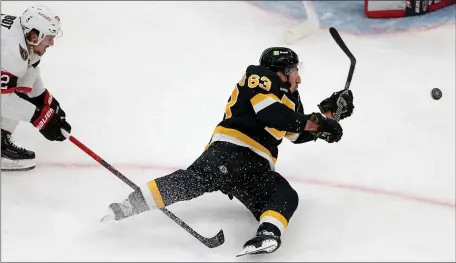  ?? MATT STONE — BOSTON HERALD ?? Brad Marchand #63 of the Boston Bruins gets tripped by Alex DeBrincat #12 of the Ottawa Senators during the NHL game at the TD Garden on February 20, 2023 in Boston, Massachuse­tts