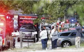  ?? TULSA WORLD VIA AP ?? People look on as Broken Arrow, Okla., police and fire department investigat­e the scene of a fire with multiple fatalities Thursday. Eight people were found dead at the Tulsa-area house, and police said they were investigat­ing the deaths as homicides.