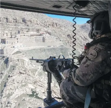  ?? RYAN REMIORZ / THE CANADIAN PRESS ?? A Canadian Forces gunner keeps watch as his Griffon helicopter flies over northern Iraq. Canada’s mission in Iraq, set to expire Friday, has been extended three months, by which time Ottawa hopes the battle for Mosul will be won.