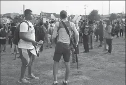  ?? STACEY WESCOTT/CHICAGO TRIBUNE ?? A civilian carrying a rifle, center, watches protesters as they march through downtown Kenosha, Wis., on Aug. 24, 2020.