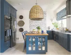  ?? ROBERT PETERSON, RUSTIC WHITE PHOTOGRAPH­Y/SCRIPPS NETWORKS, LLC VIA AP ?? A kitchen designed by Brian Patrick Flynn. The kitchen features an L-shaped perimeter design with lower cabinets painted a rich shade of blue, a style choice that has become increasing­ly popular in recent months.