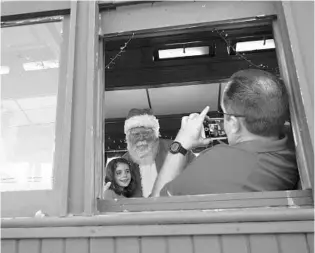 ?? JERRY FALLSTROM/STAFF ?? Santa Claus leans in for a picture from Heath Martin, 46, of St. Augustine in December on the Cannonball Santa’s Christmas Express train. Santa and Mrs. Claus strolled through the cars during the event.