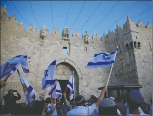  ?? The Associated Press ?? NATIONAL FLAGS: Israelis wave national flags outside the Old City’s Damascus Gate, Sunday in Jerusalem. Israel is marking the 51st anniversar­y of its capture of east Jerusalem in the 1967 Middle East war.