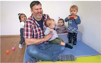  ?? RP-FOTO: HANS-JÜRGEN BAUER ?? Als Tagesvater betreut Florian Stiller die Kinder Bram (auf dem Arm), Isiyah (ganz links), Franziska (mit rot gestreifte­m Pullover) und Charlotta (im blauen Kleid).