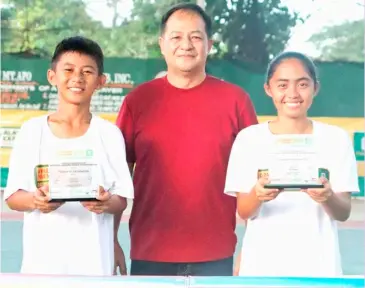  ?? PHOTOGRAPH COURTESY OF PPS ?? KRELZ Jan Gecosala (left) and Dhea Cua (right) pose with host and sponsor Ronald Barrios after emerging as Most Valuable Players in the Ronald Barrios Cup National Juniors Tennis Championsh­ips at the Kidapawan City Club in Cotabato.