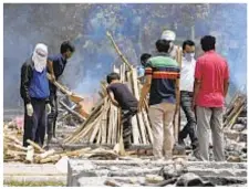  ??  ?? Mass cremations, burials and funeral pyres are a grimly common sight Tuesday in COVIDravag­ed India, where deaths and cases continue to mount. Far left, a patient breathes with the help of oxygen under a tent along roadside.