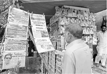  ??  ?? Pakistani residents read morning newspapers at a stall a day after the general election in Islamabad. — AFP photo