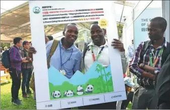 ?? CHEN CHENG / XINHUA ?? Delegates of the Third United Nations Environmen­t Assembly pose for a photograph at the exhibition booth of Sina Weibo in Nairobi, Kenya, on Sunday. The poster they held was for a micro blog calling for protection of pandas. Several Chinese companies...
