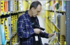  ?? MARK LENNIHAN — THE ASSOCIATED PRESS ?? A clerk picks an item from a shelf and scans it with a handheld device to fill a customer order at the Amazon Prime warehouse in New York.