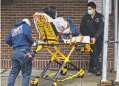  ?? JOHN MINCHILLO ASSOCIATED PRESS ?? Emergency medical workers wear protective masks due to COVID-19 concerns while delivering a patient Sunday to the emergency room at Brooklyn Hospital Center in New York.