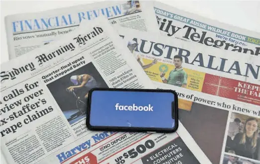  ?? LUKAS COCH / EFE ?? ➤➤ Digitaliza­ción
➤ móvil con el logo de Facebook destaca ante la cabecera de varios periódicos australian­os.